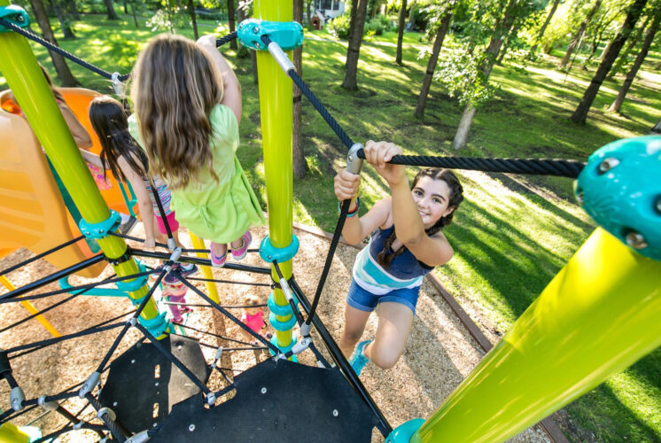two girls climbing on netted playground structure