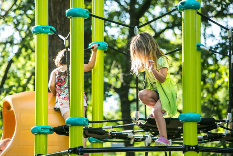 two young girls playing on netted playground structure