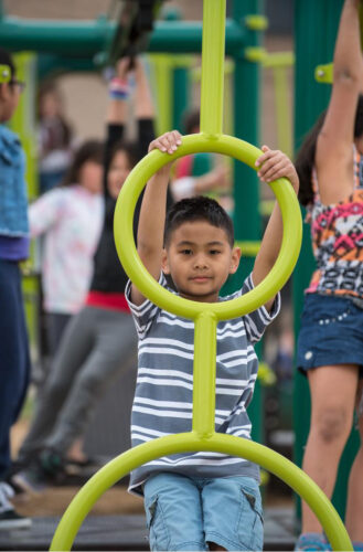 Boy playing on circular climbing playground equipment