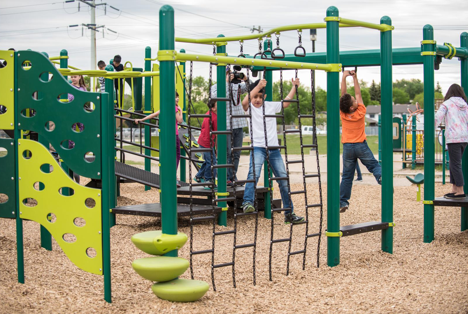 Kids on climbing rope wall attached to larger play structure.