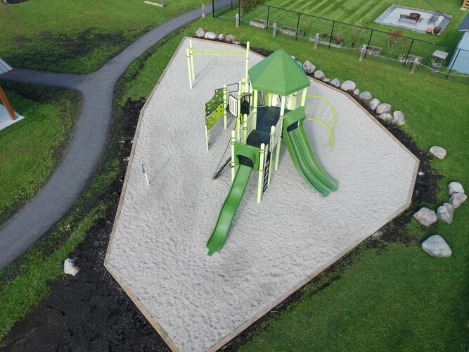 Bright green playground structure with multiple slides and climbing features.